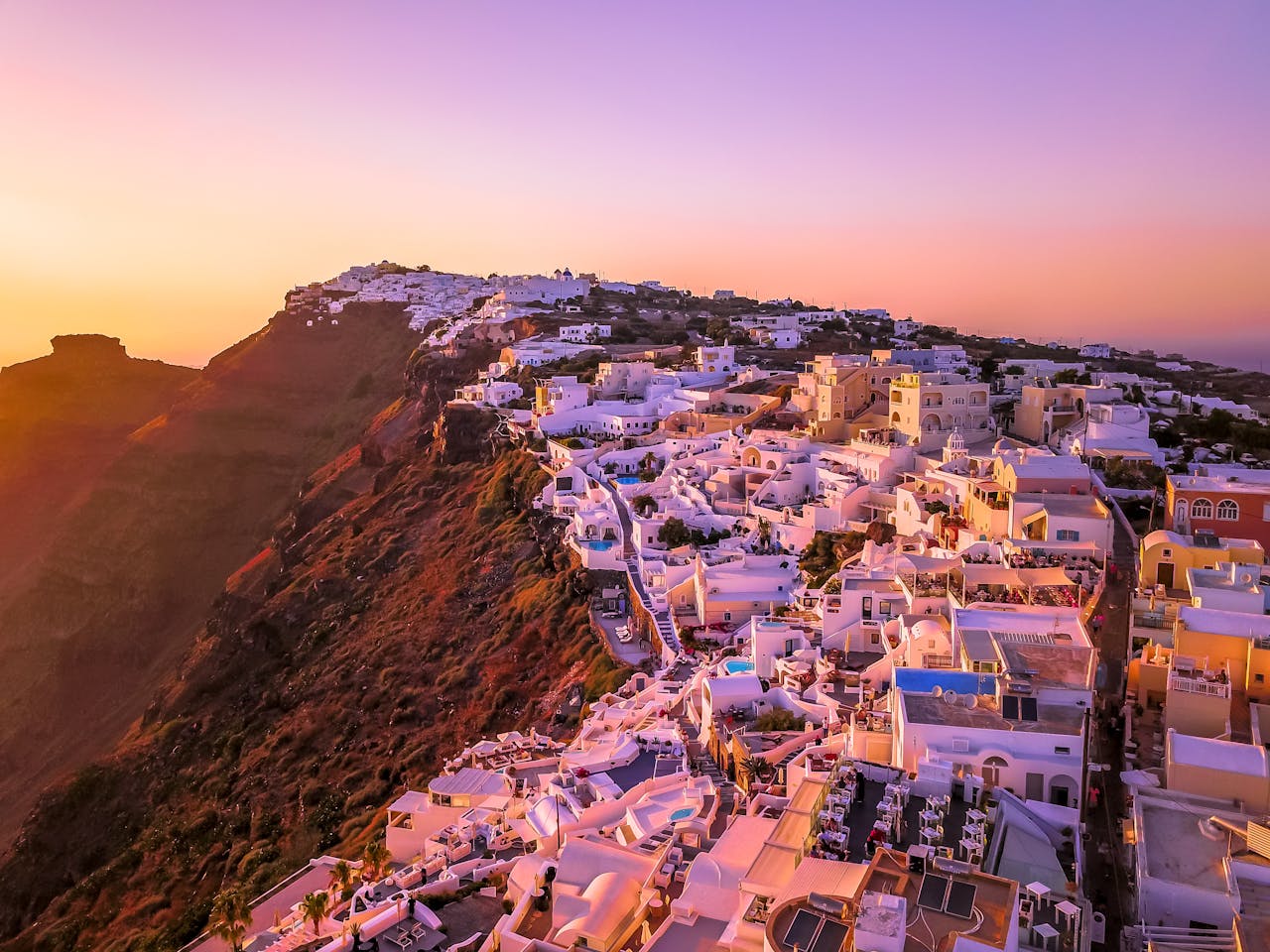 A breathtaking aerial view of Santorini at sunset showcasing iconic architecture and vibrant colors.
